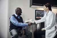 African American older man shaking hands with female dentist