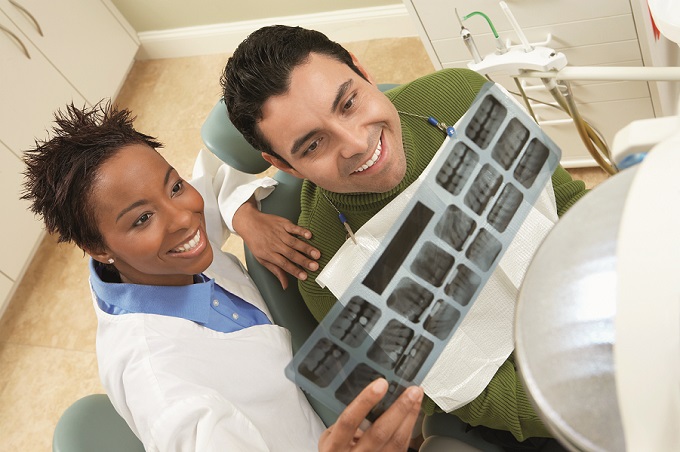 Black woman dentist going over dental x-rays with male patient