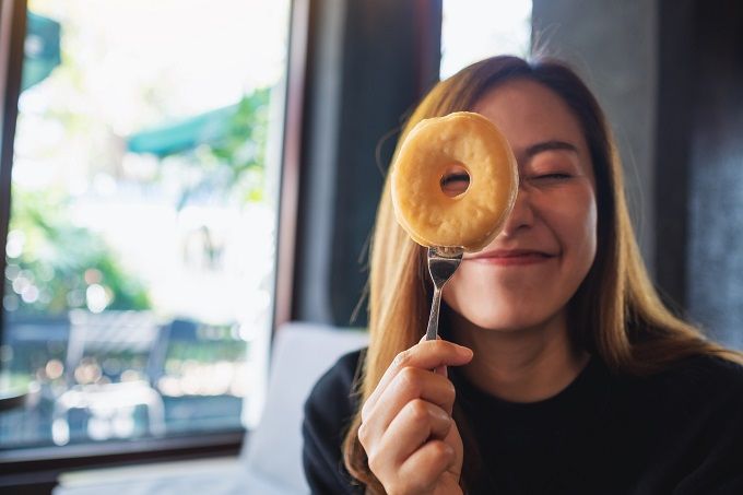 young white woman holding up a sugary donut on a fork