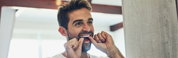 man flossing teeth