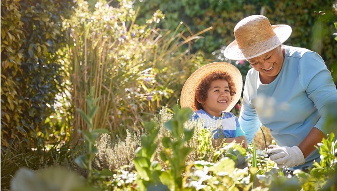 Black older woman with younger black boy gardening in a garden