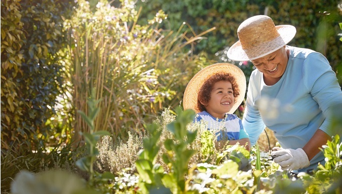 Black older woman with younger black boy gardening in a garden