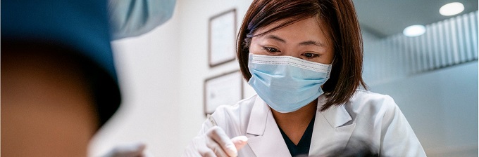 Woman dentist wearing a mask, treating a patient