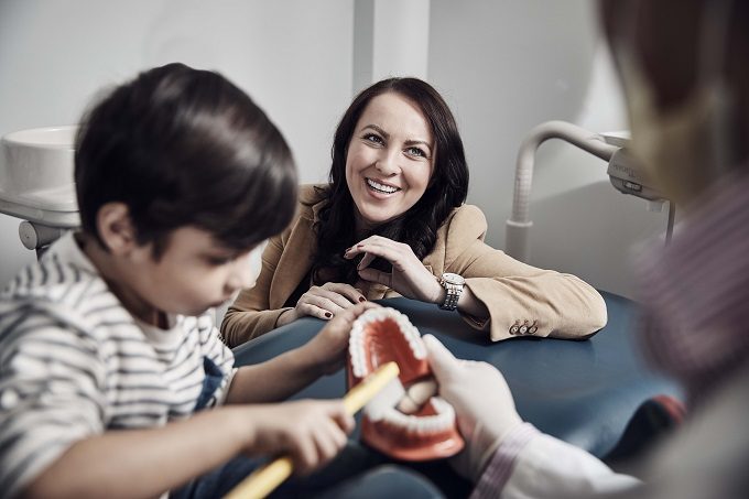 Young boy brushing dental teeth with his mom in a dental office