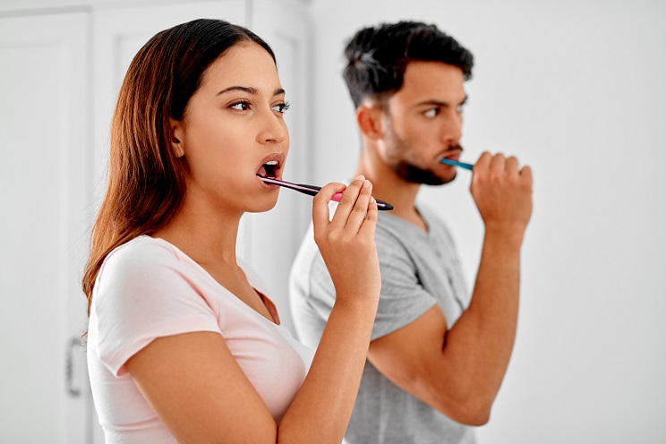 man and woman brushing teeth