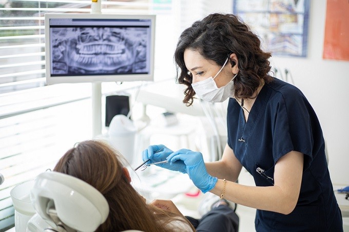 White female dentist working on a white female patient in dental office