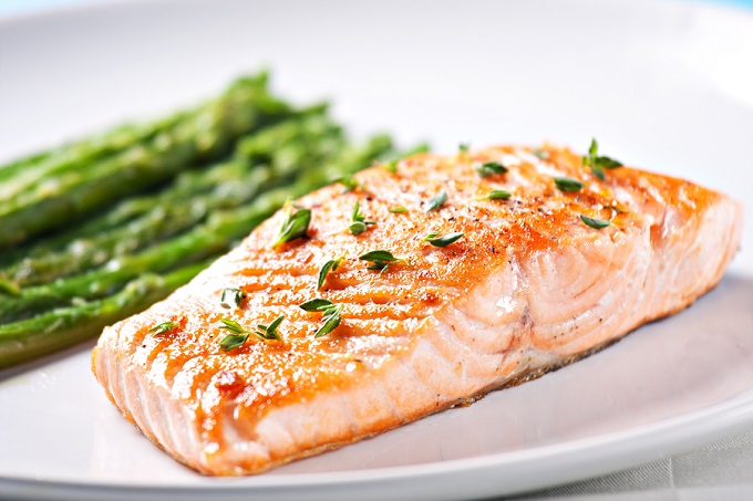 Baked salmon serving on a plate with asparagus as a side