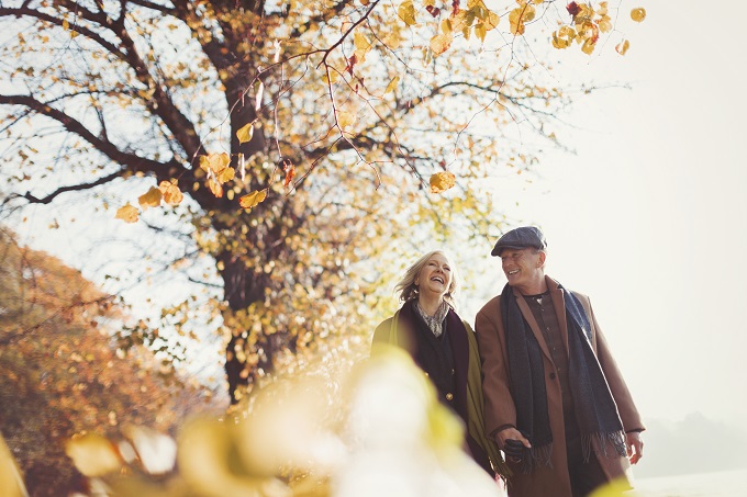 Older man and woman walking outside with the leaves changing for fall