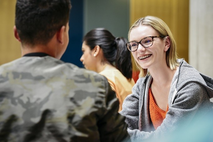 photo of three mixed adolescent students talking and smiling