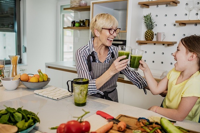 White female adult with white young girl making green smoothies, smiling and cheering
