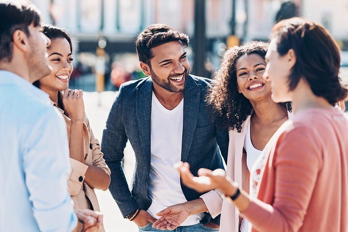 Mixed young adults in open circle talking and smiling outside