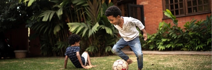 Two Black young boys playing soccer outside