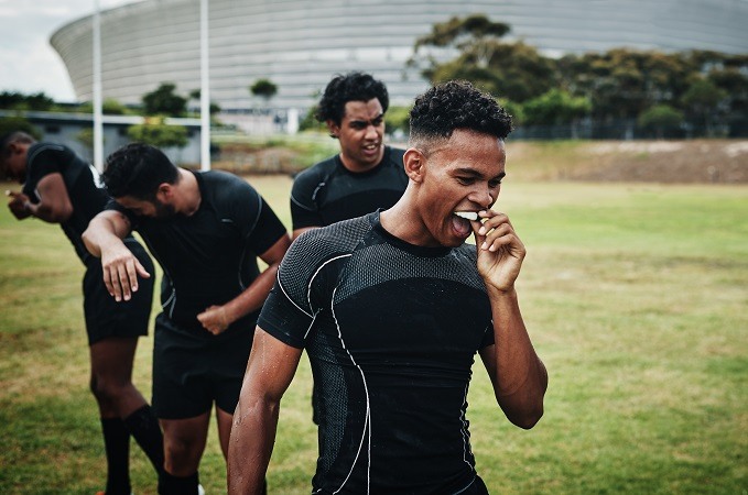 Male athletes working out and one wearing a mouth guard