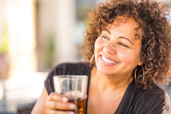mixed woman with curly hair holding a soda drink