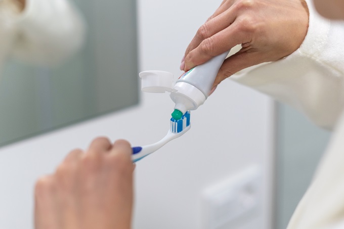Squeezing out toothpaste onto a toothbrush