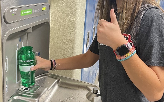 H2O Water bottle filling station and white female middle school student filling up a water bottle 