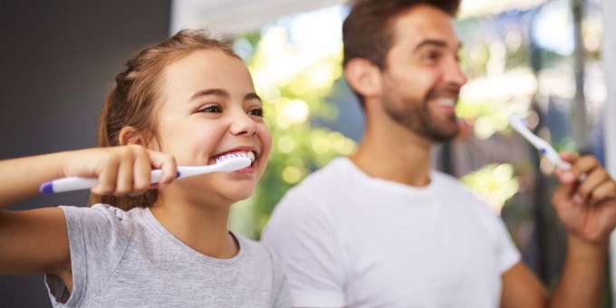 father and daughter brushing teeth