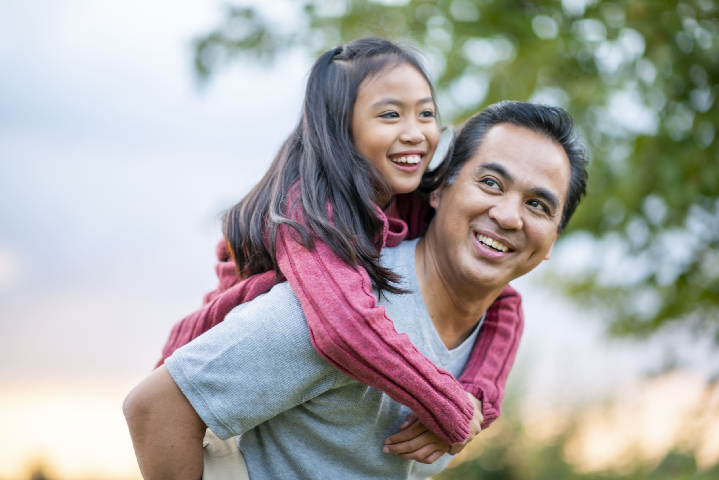 Father holding child daughter both smiling outdoors