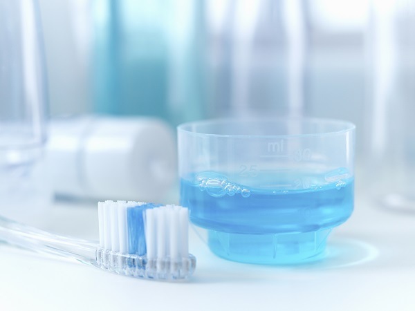 photo of a toothbrush and cup of blue mouthwash for oral hygiene