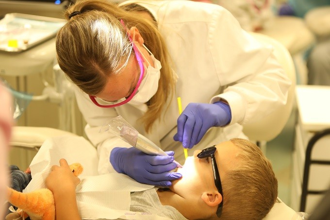 Female white dentist working on young white boy's teeth