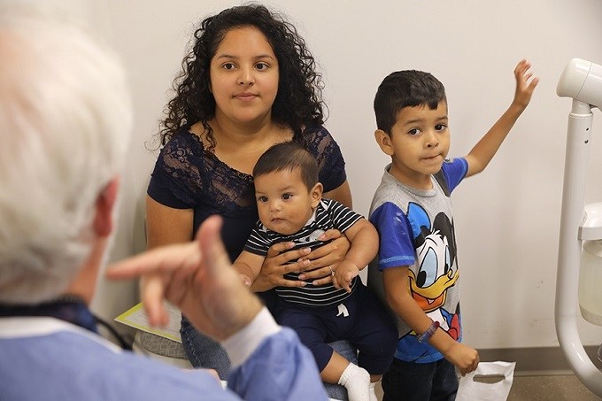 Hispanic mother with two children speaking to a dentist