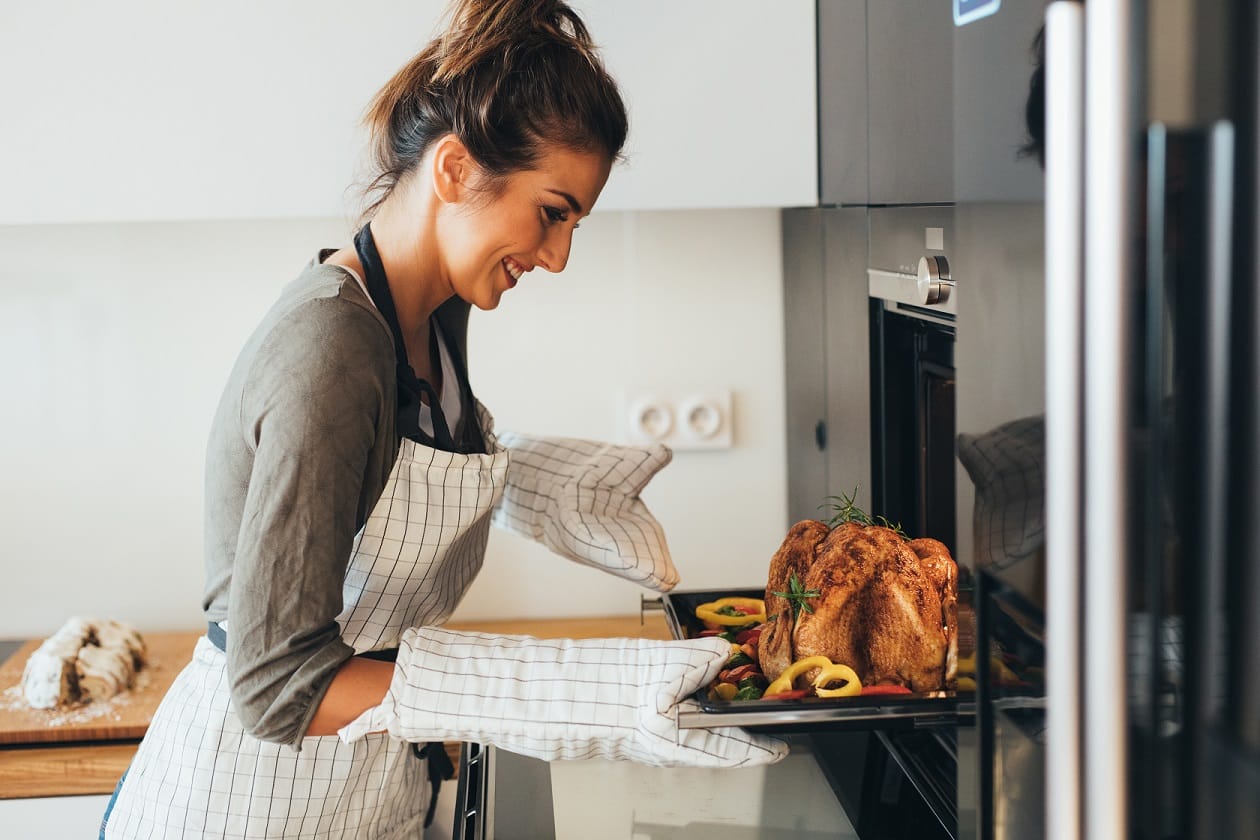 young adult white female at kitchen oven cooking a turkey